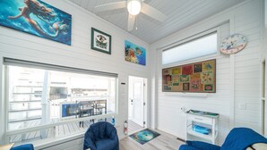 Une pièce spacieuse avec une grande fenêtre, un ventilateur de plafond et une horloge au mur.
