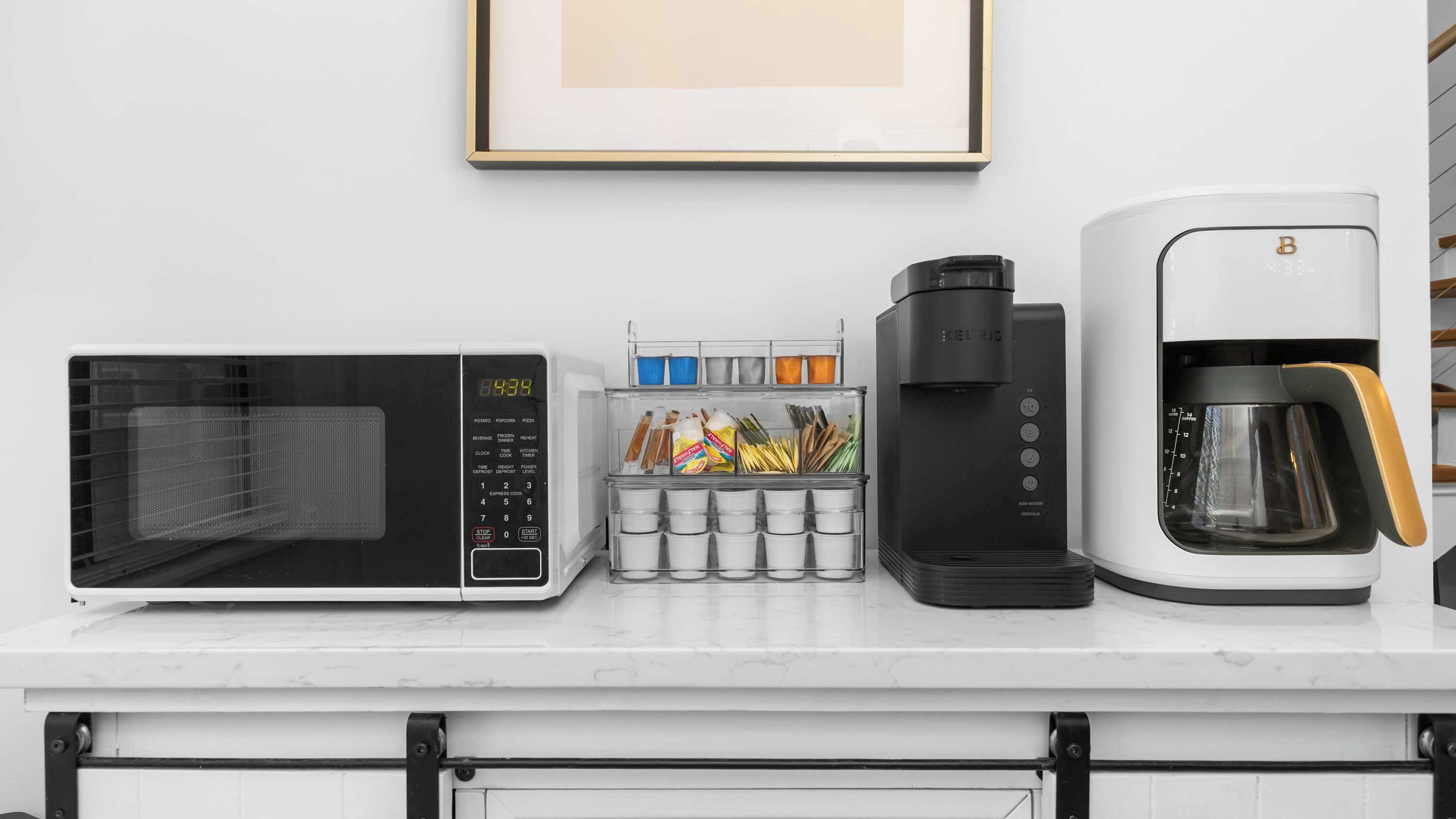 A kitchen counter with a microwave, coffee maker, and a spice rack.