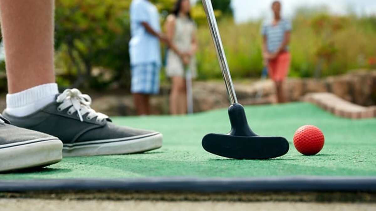 A close-up of a golf putting green with a putter and a golf ball.
