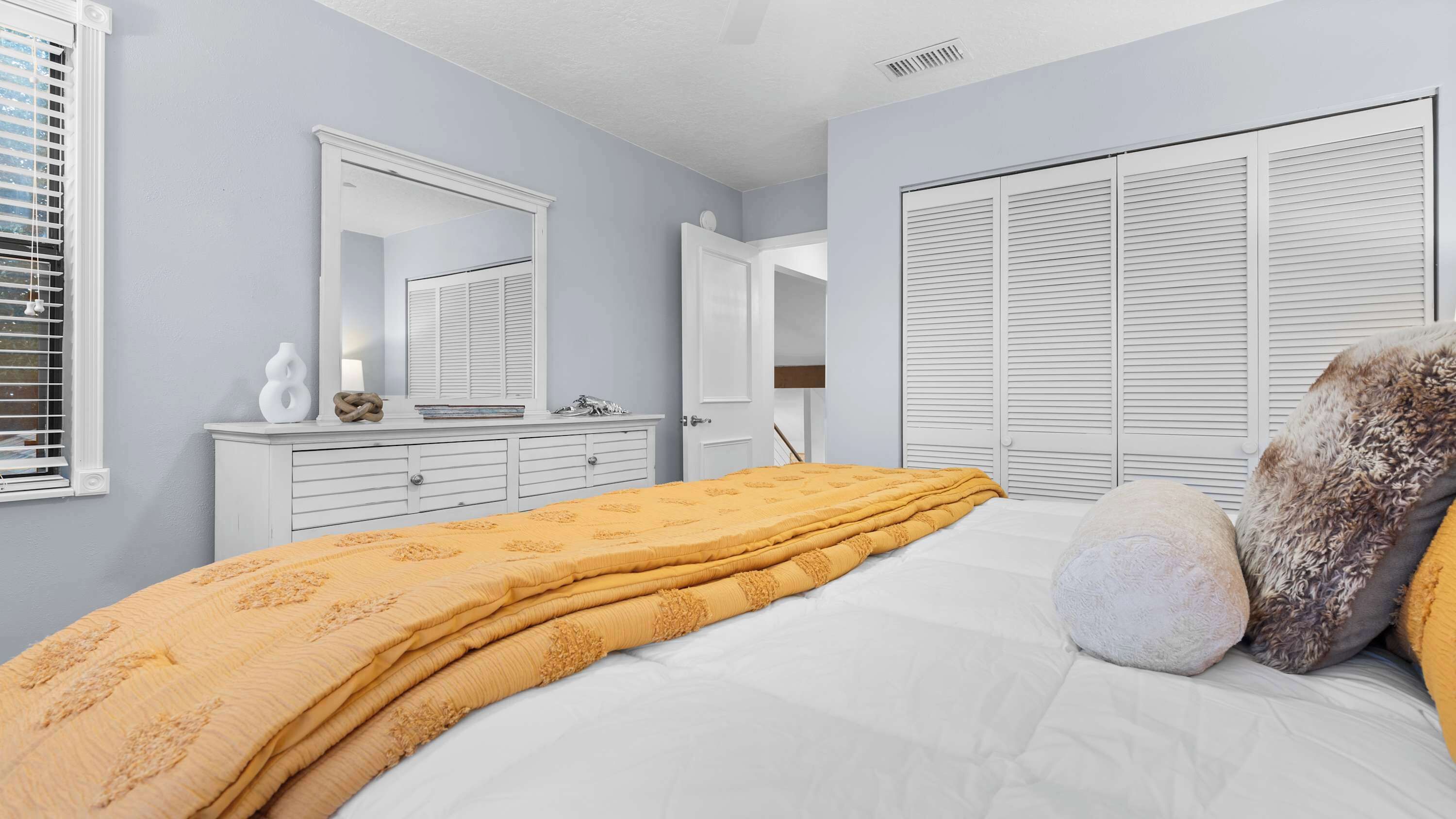 A bedroom with a bed, a dresser, a mirror, and a wardrobe.