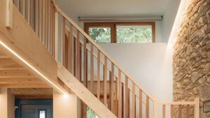 Een modern interieur met een houten trap, een donkere bank en een stenen muur.