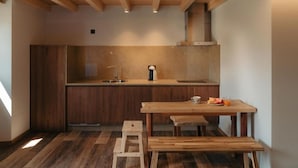 Een kleine keuken met houten kastjes, een spoelbak en een ontbijttafel met een bankje.
