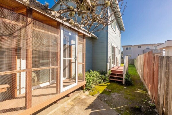 A residential property with a covered outdoor area, a wooden fence, and a small garden.