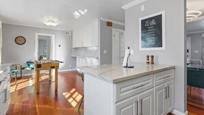A modern kitchen with white cabinets, a foosball table, and a dartboard. - @ Marbella Lane - Buckingham Place Laundry + P (Pacifica)