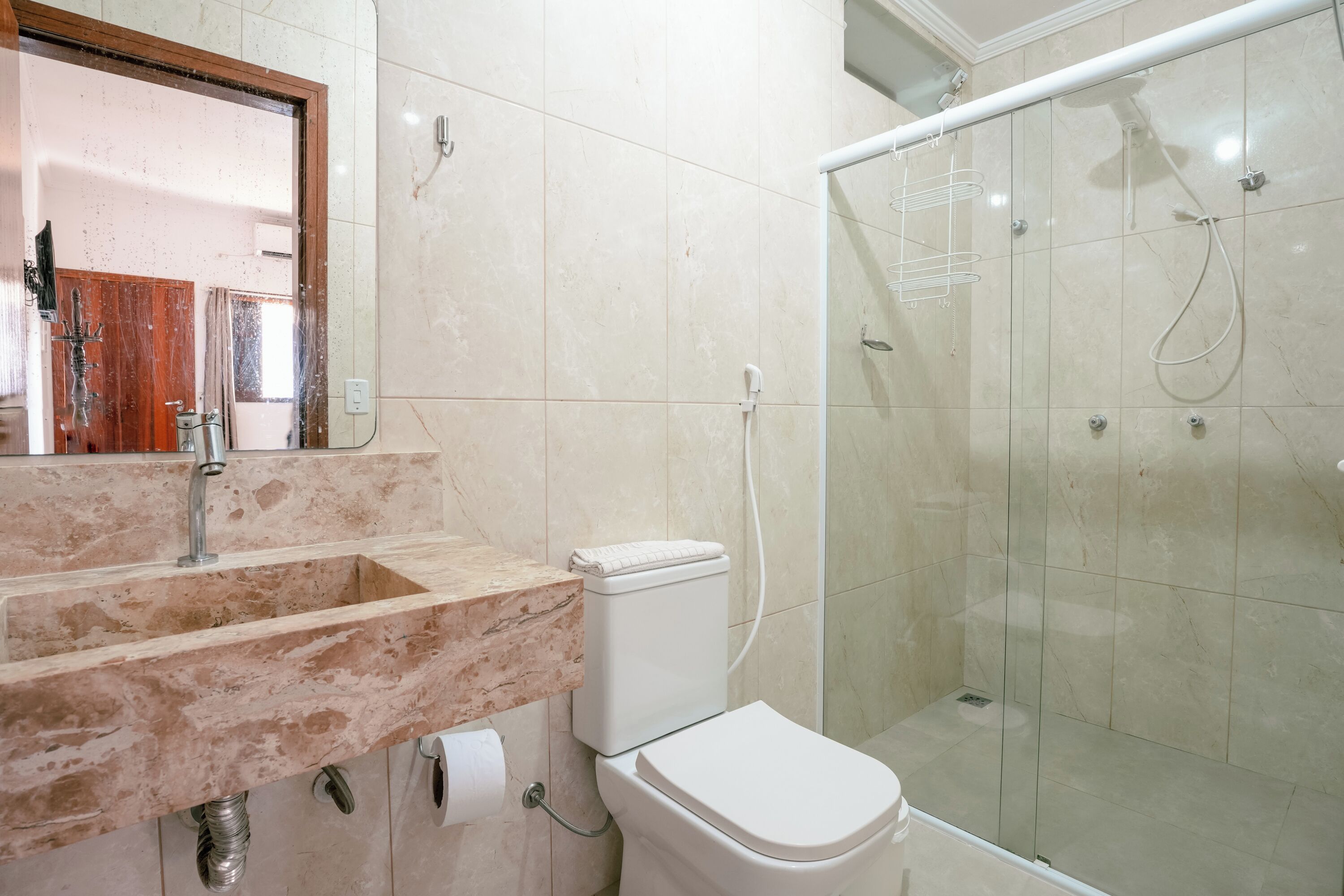A bathroom with a marble sink, toilet, and a glass-enclosed shower area.