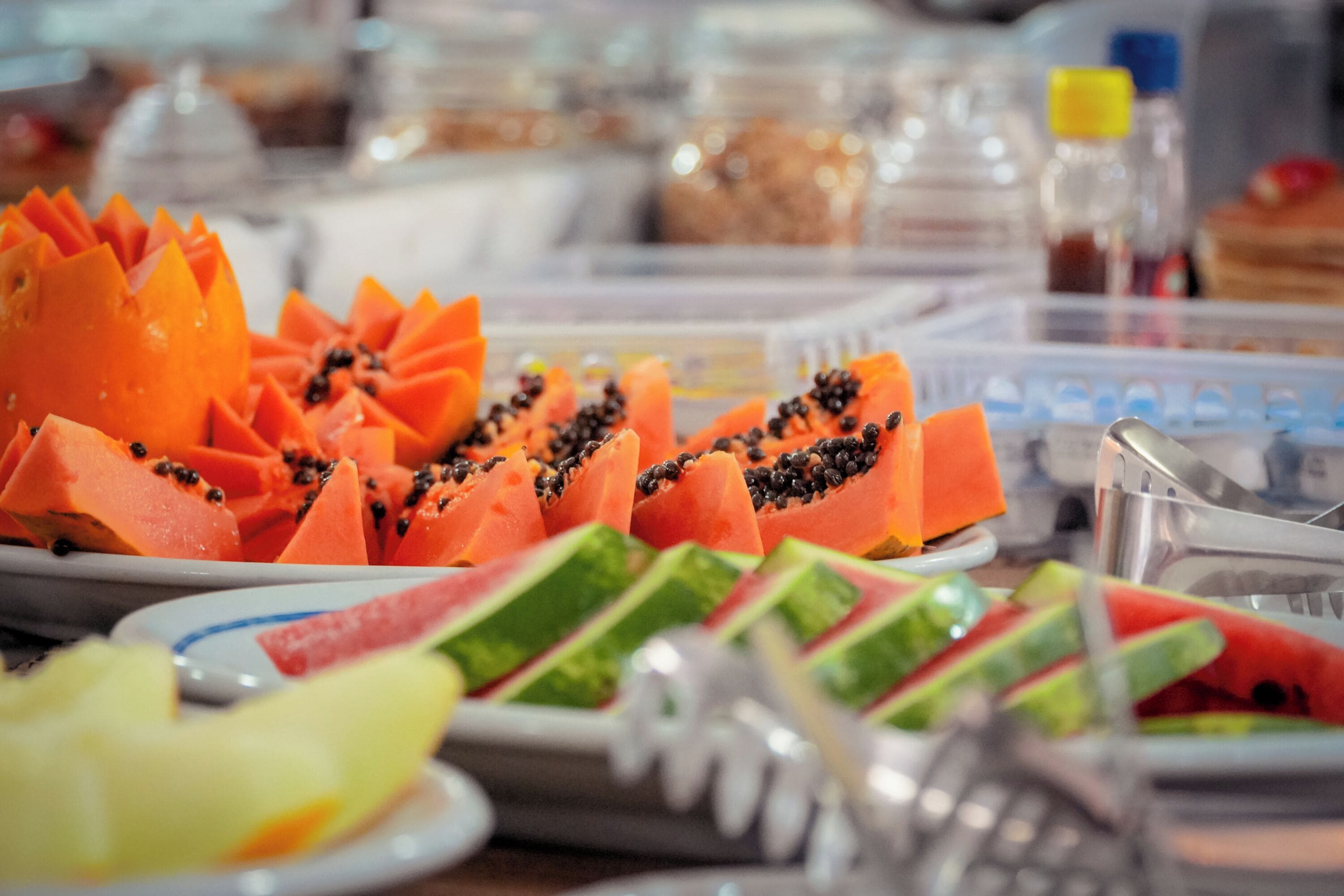 A buffet with various fruits including papaya and watermelon.