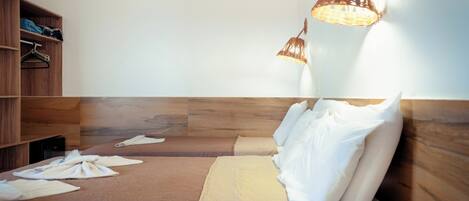 Een hotelkamer met een houten bed, witte kussens en een hanglamp.