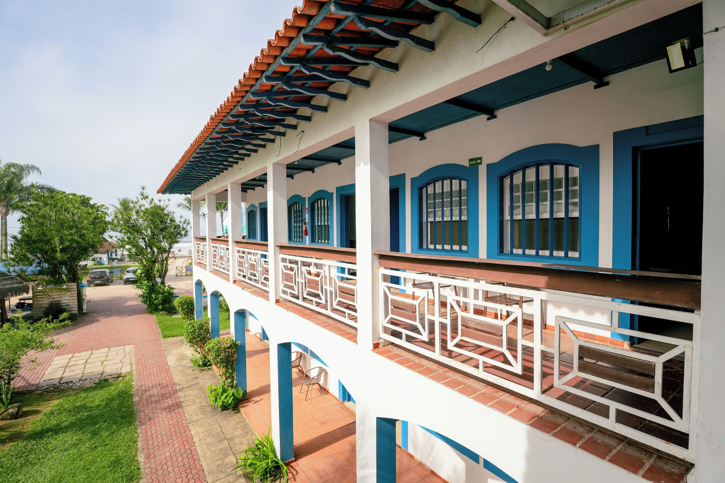 A building with a covered walkway, white and blue exterior, and a tiled roof.