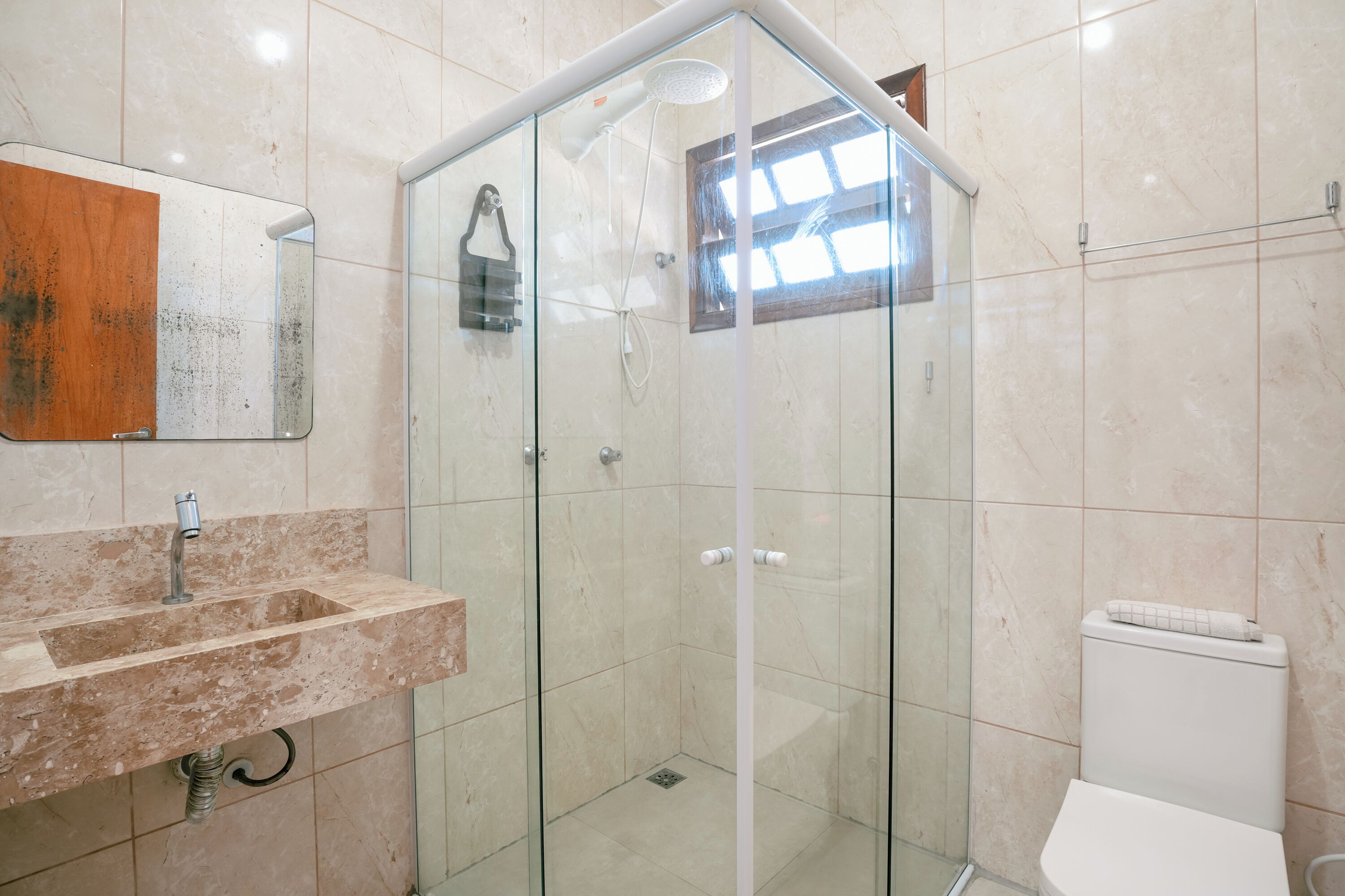 Une salle de bain avec une douche à parois de verre, un lavabo doté d’un plan de toilette en marbre et des toilettes.