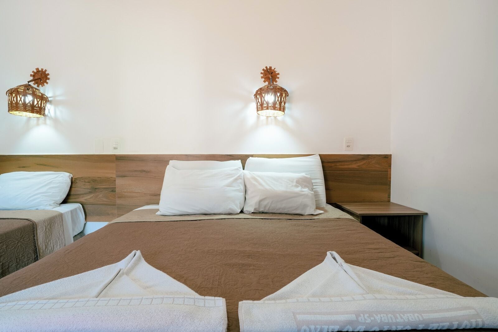 A hotel room with a large bed, two bedside tables, and two wall-mounted lamps.
