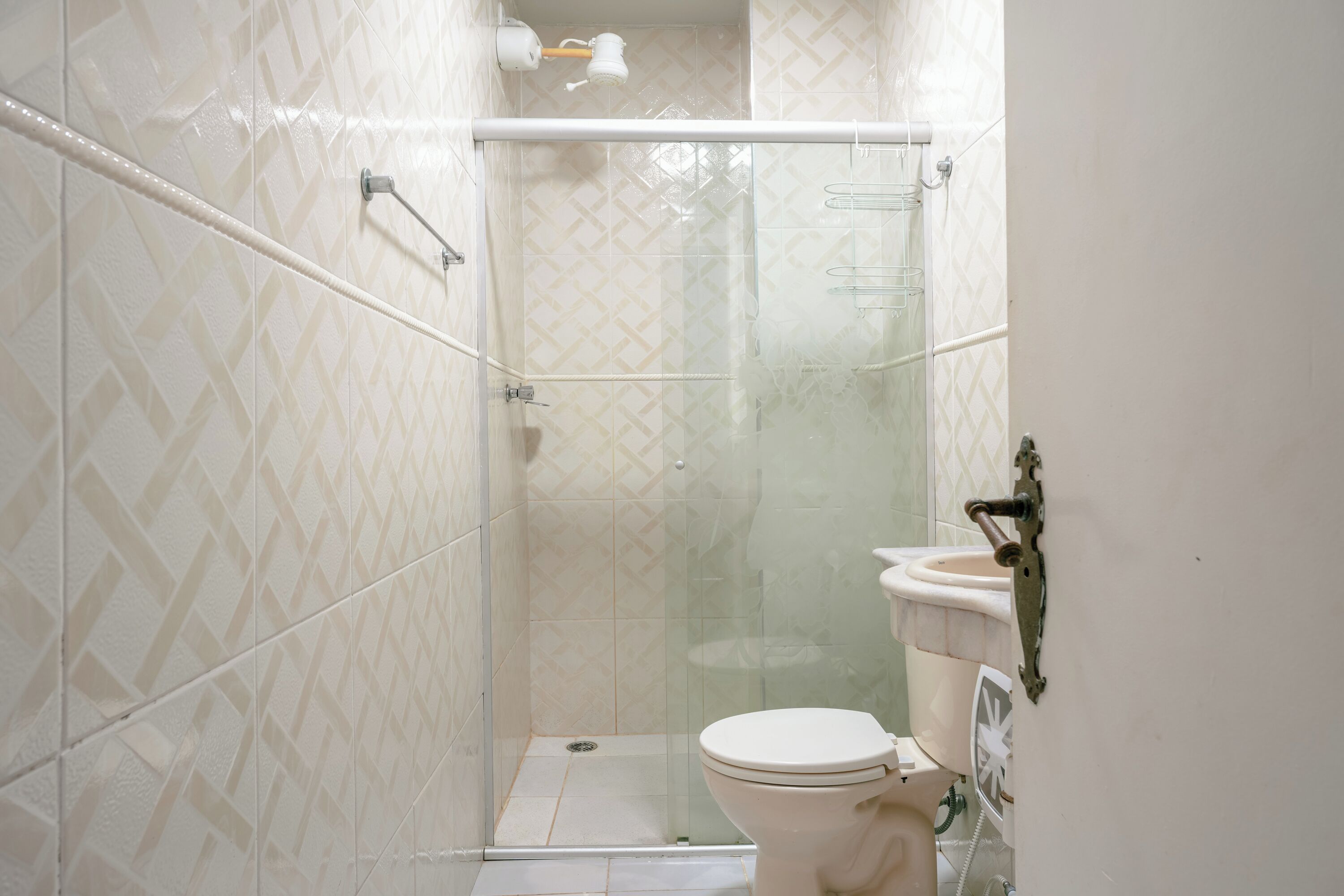 Un baño con ducha acristalada, inodoro y lavamanos.