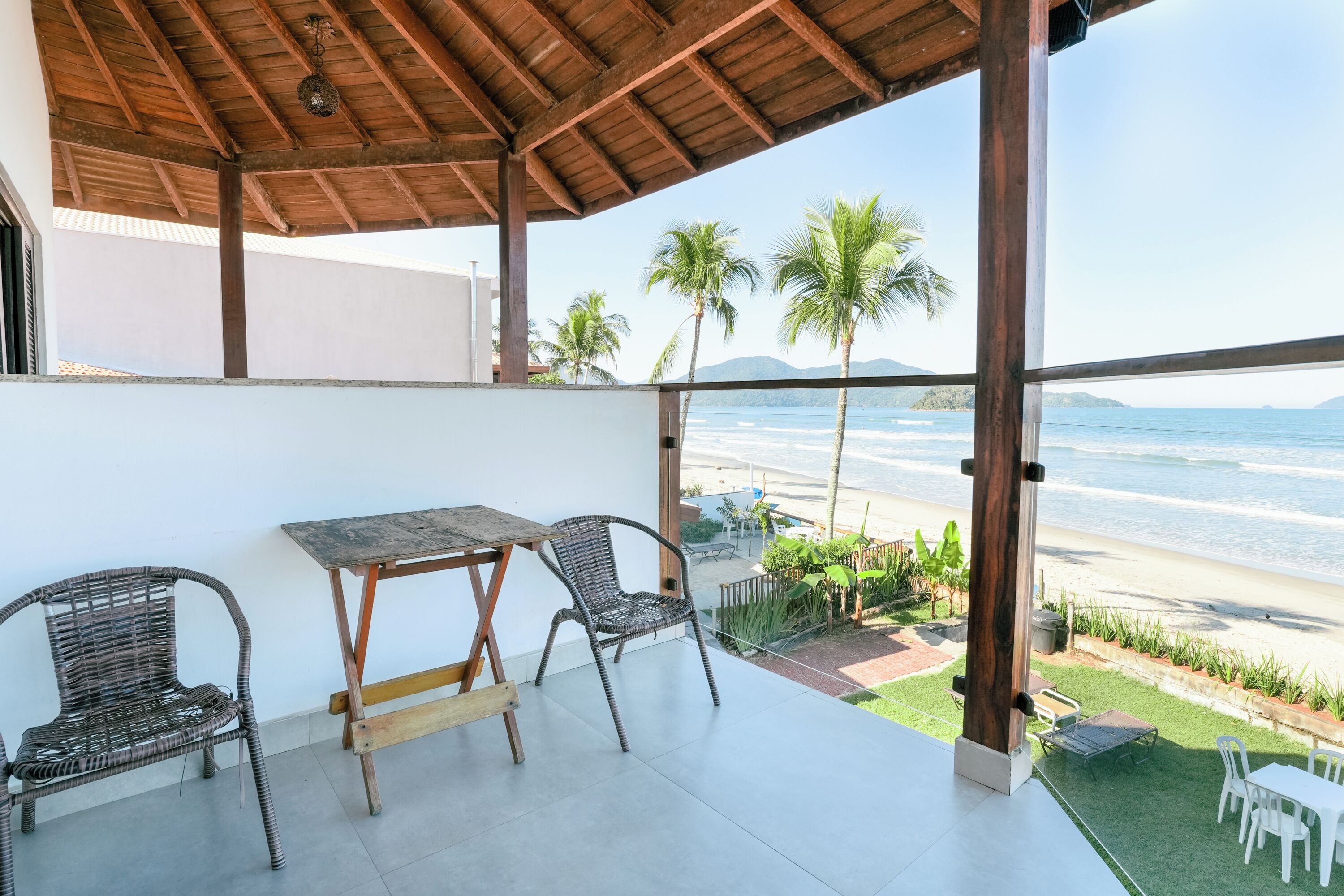 A covered outdoor seating area with a view of the beach and ocean.