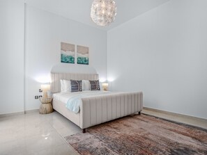 A bedroom with a large bed, two bedside lamps, a textured rug, and a chandelier. - Easygo-upgraded 1bdr Polo Residence (Dubai)