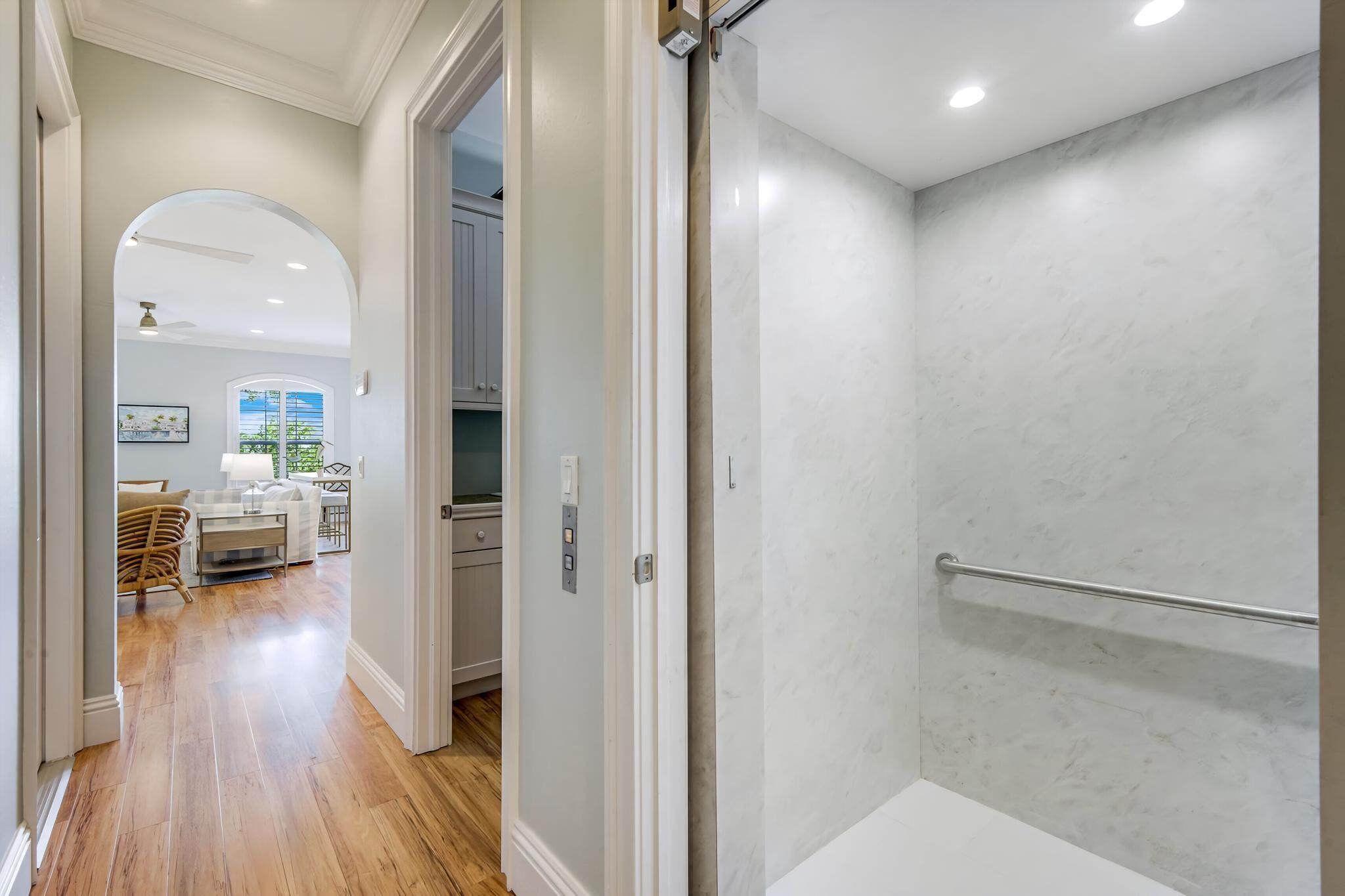 Un baño moderno con ducha, toallero y vistas a un área de estar con mesa y sillas.