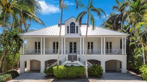 A two-story white building with a balcony, arched doorways, and a central staircase. - Stunning bayside retreat with golf cart! (Captiva)
