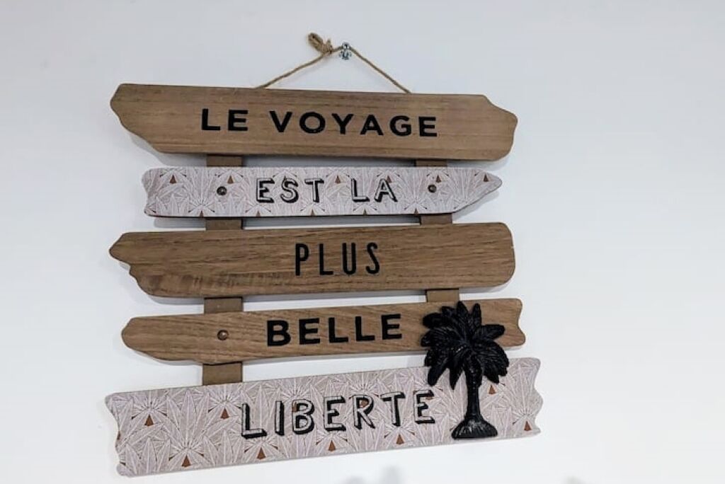 A wooden sign with the text "LE VOYAGE EST LA PLUS BELLE LIBERTE."