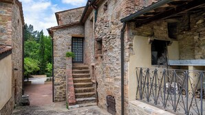 A narrow stone pathway leading to a building with a wooden door and steps. - Mulino Di Amarrante Countryhouse  (Montaione)