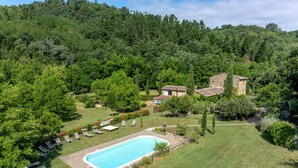 A pool surrounded by lawn chairs and a small building with a tiled roof. - Mulino Di Amarrante Countryhouse  (Montaione)