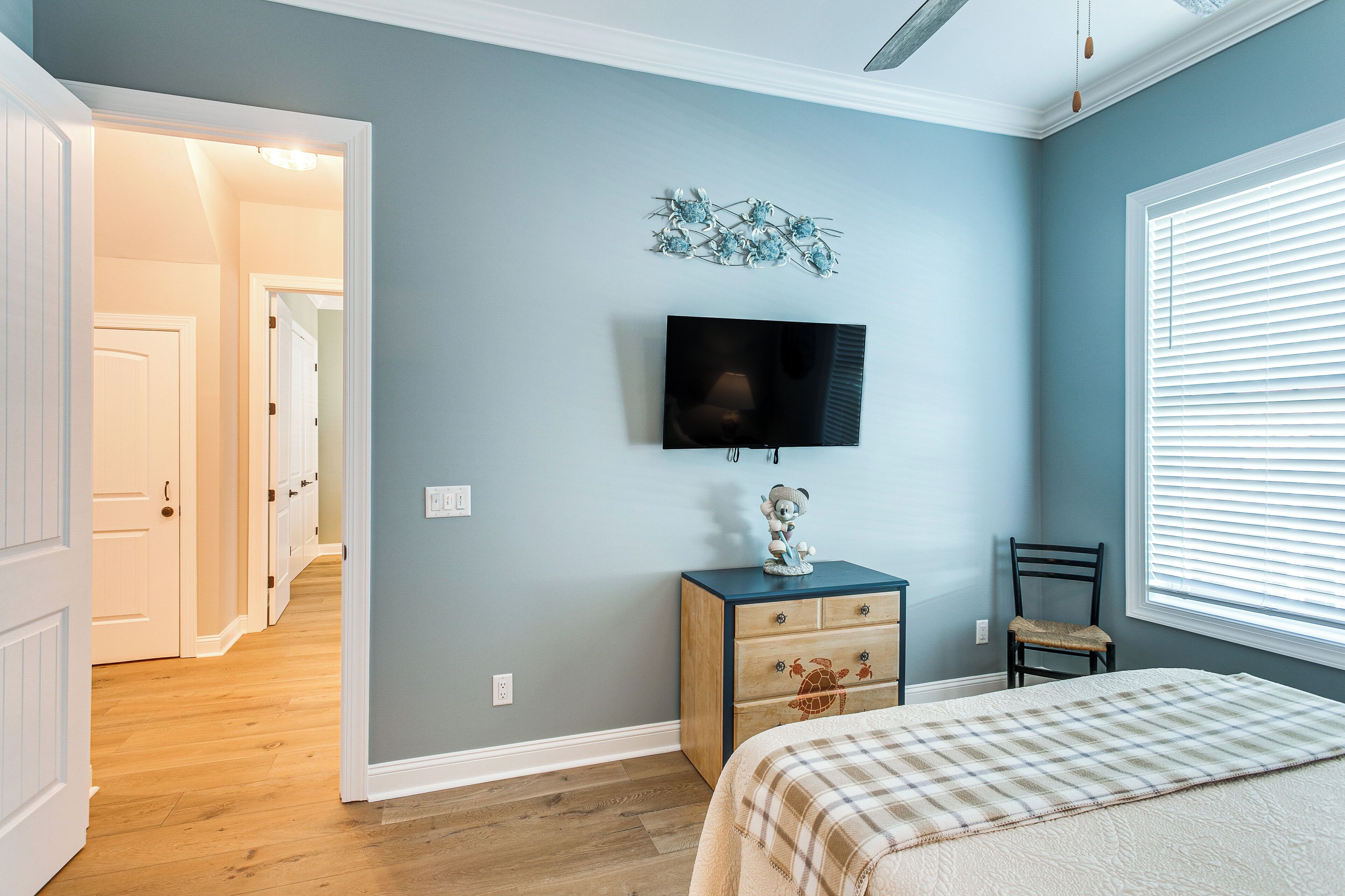A bedroom with a bed, a dresser, a chair, a television, and a decorative wall piece.