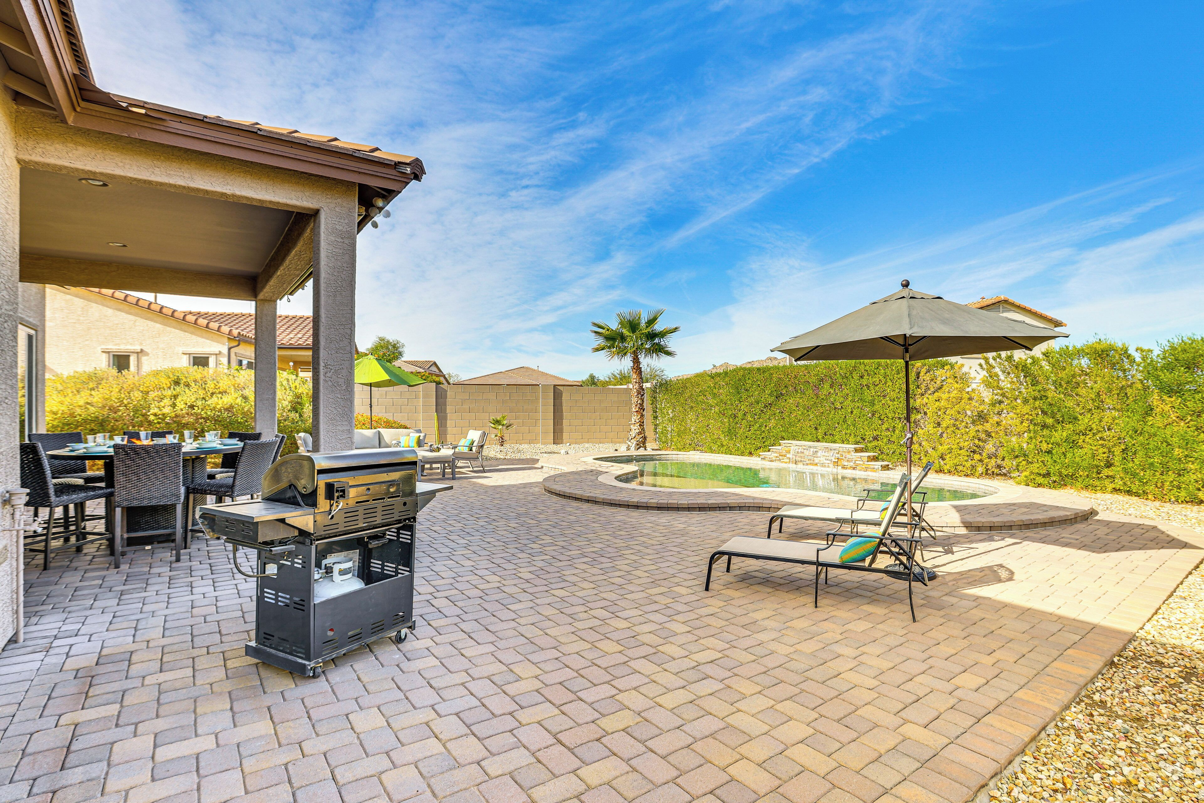A patio with a grill, outdoor seating, and a swimming pool.