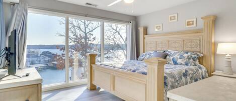 Quarto com uma janela grande, cama, escrivaninha e cadeira.