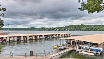 A marina with boats docked, a covered area, and a view of a lake with hills in the background.