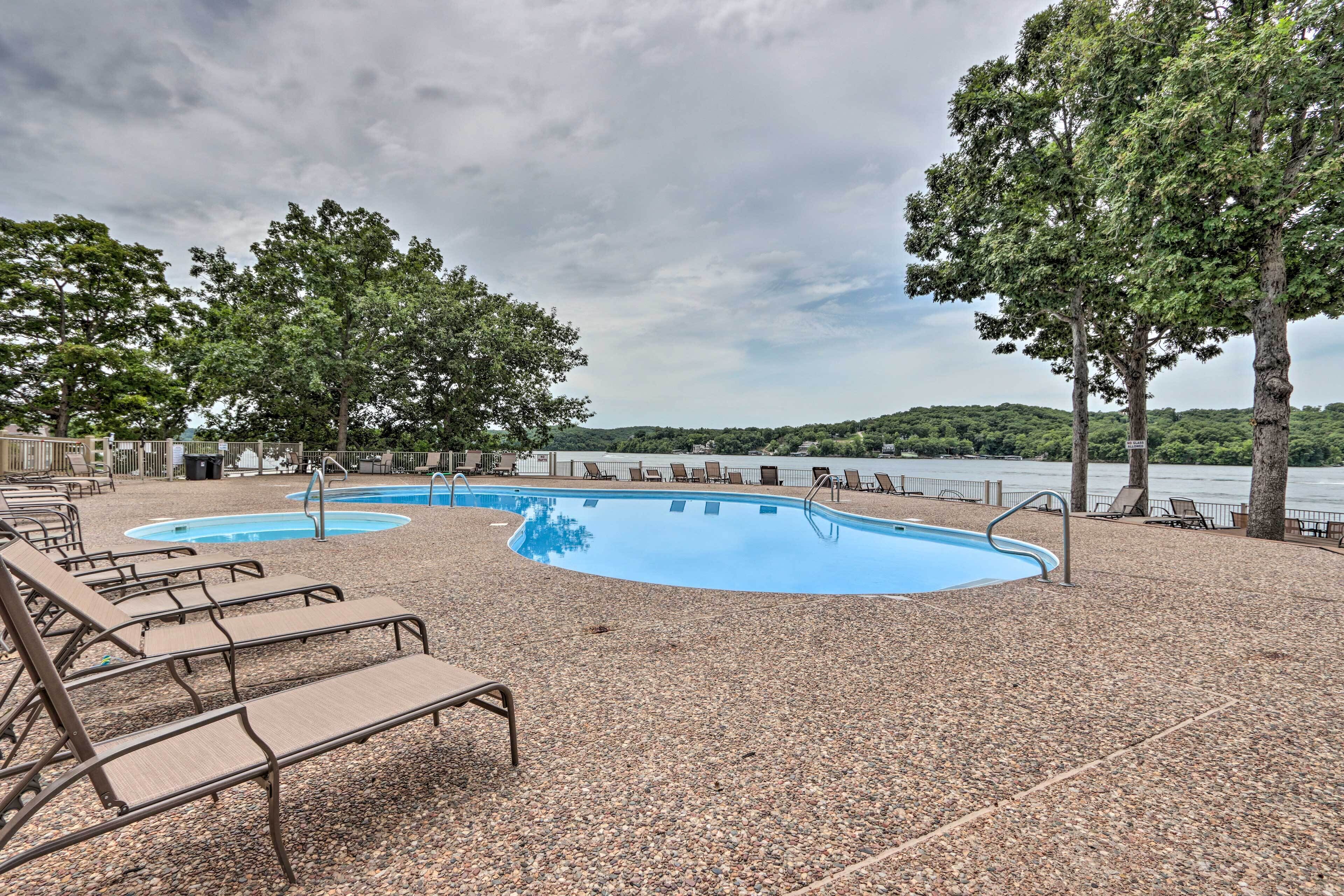 A pool area with lounge chairs and a view of a lake.