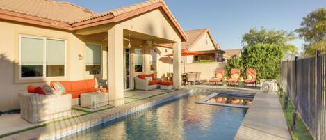 A residential pool area with outdoor seating and a covered patio.
