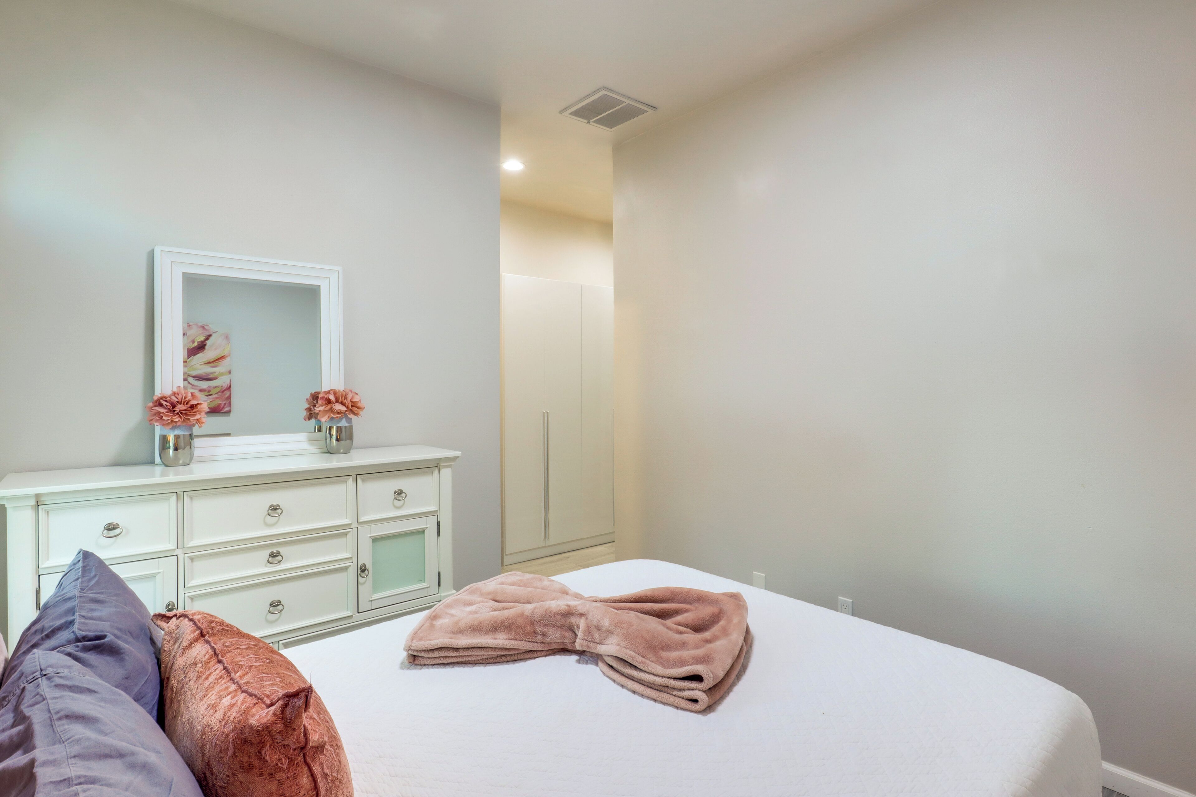A bedroom with a bed, a dresser, a mirror, and a door.
