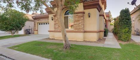 A residential house with a garage, a tree in front, and a well-maintained lawn.