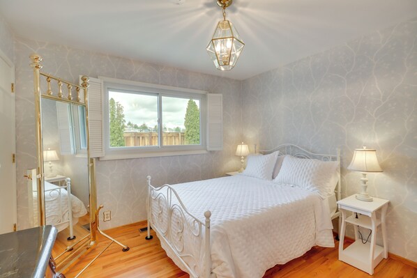 A bedroom with a white bed, a nightstand with a lamp, a mirror, and a window with shutters. - 2 Living Areas + Library! Home 22 Mi to Mt Rose (Reno)
