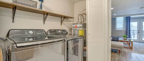 Un área de lavandería con dos lavadoras Samsung, un estante de madera y un radiador.