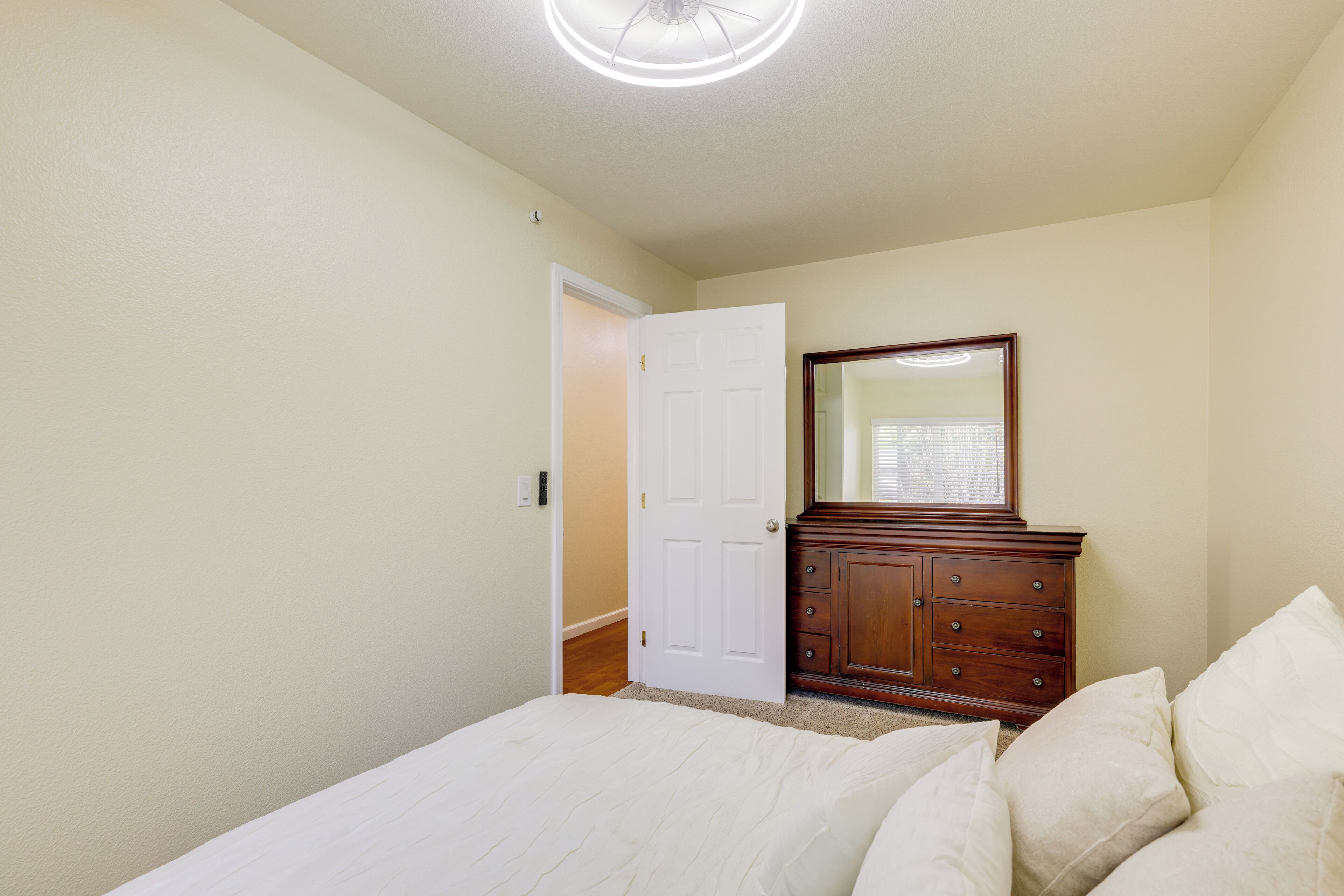 Une chambre à coucher avec un lit, une commode, un miroir et une porte.