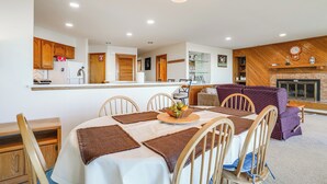 A dining area with a table set for four, surrounded by wooden chairs, a chandelier, and a fireplace. - 1 Mi to Wintergreen Resort: Mtn-view Condo! (Nellysford)