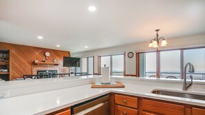 A modern kitchen with wooden cabinetry, a white countertop, and a large window offering a view of the outdoors. - 1 Mi to Wintergreen Resort: Mtn-view Condo! (Nellysford)