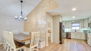 A modern kitchen with wooden flooring, a dining table with chairs, and a chandelier. - Walk to Gulf: Tranquil Home w/ Yard in Pcb! (Panama City Beach)