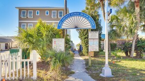 A pathway leading to a beach access sign with palm trees and a building in the background. - Walk to Gulf: Tranquil Home w/ Yard in Pcb! (Panama City Beach)