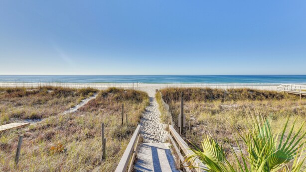 A sandy beach path leading to the ocean with a wooden boardwalk and a small wooden structure. - Walk to Gulf: Tranquil Home w/ Yard in Pcb! (Panama City Beach)