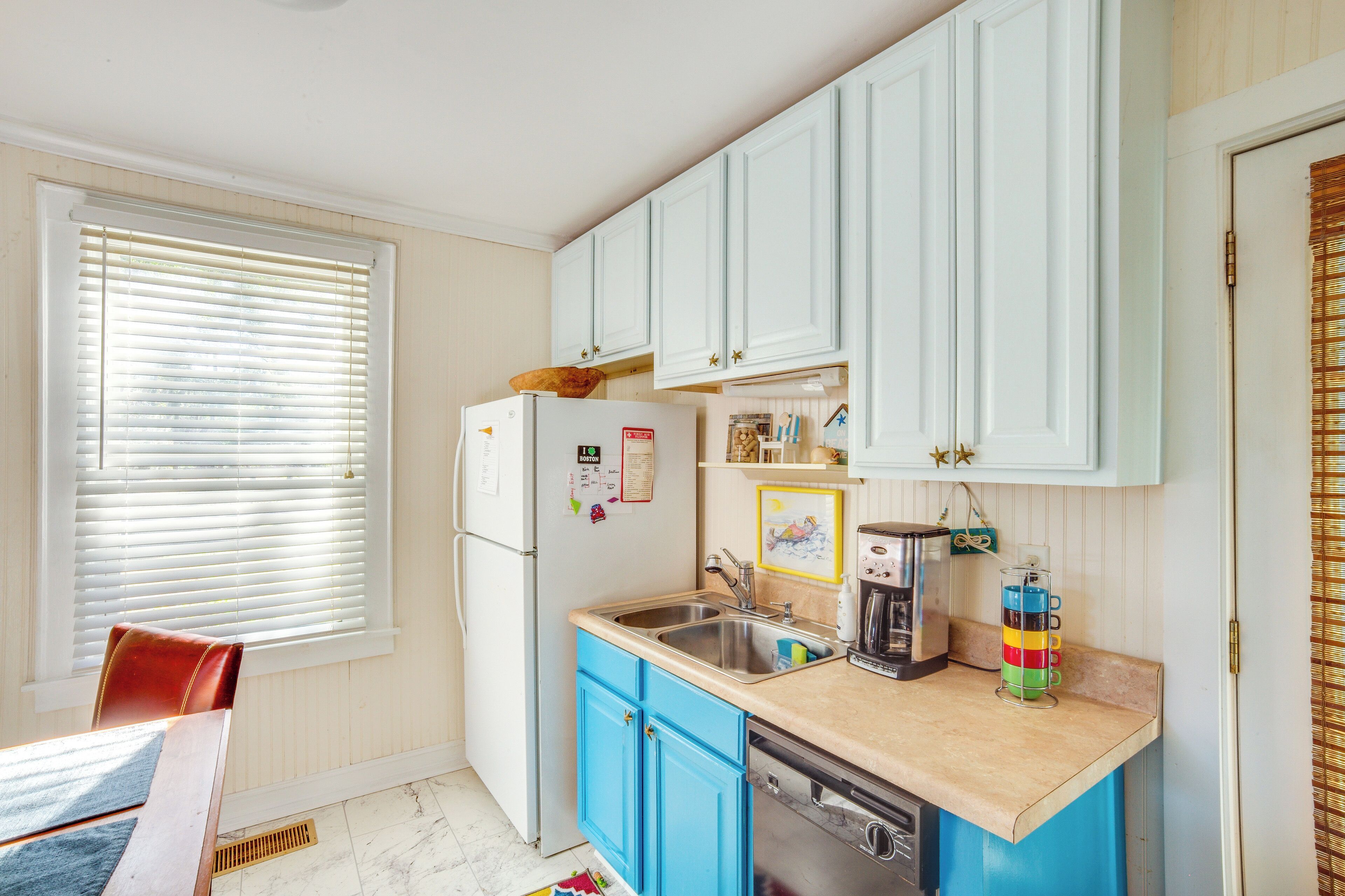 A kitchen with white cabinets, a sink, a refrigerator, and a coffee maker.