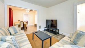 Ett vardagsrum med en soffa, ett soffbord, en tv och en matplats med ett bord och stolar.