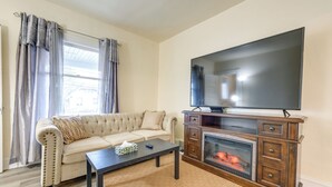 A living room with a beige sofa, a coffee table, a flat-screen TV, and a fireplace. - Apartment 2 Mi to Niagara Falls State Park! (Niagara Falls)