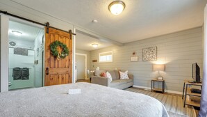 Um quarto com uma cama grande, uma porta deslizante, um sofá, uma mesinha e uma televisão.