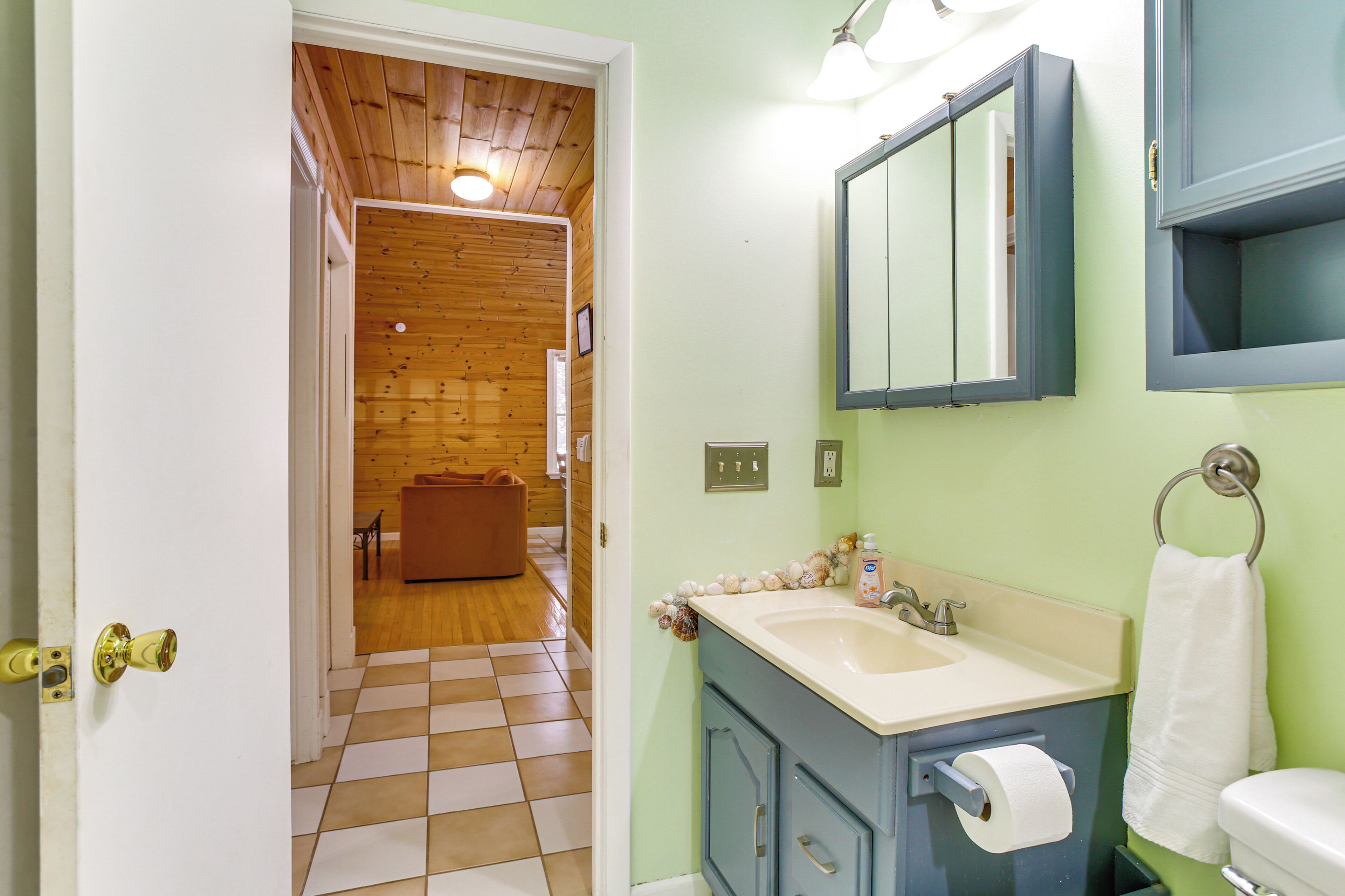 A bathroom with a checkered floor, a sink, a mirror, and a toilet.