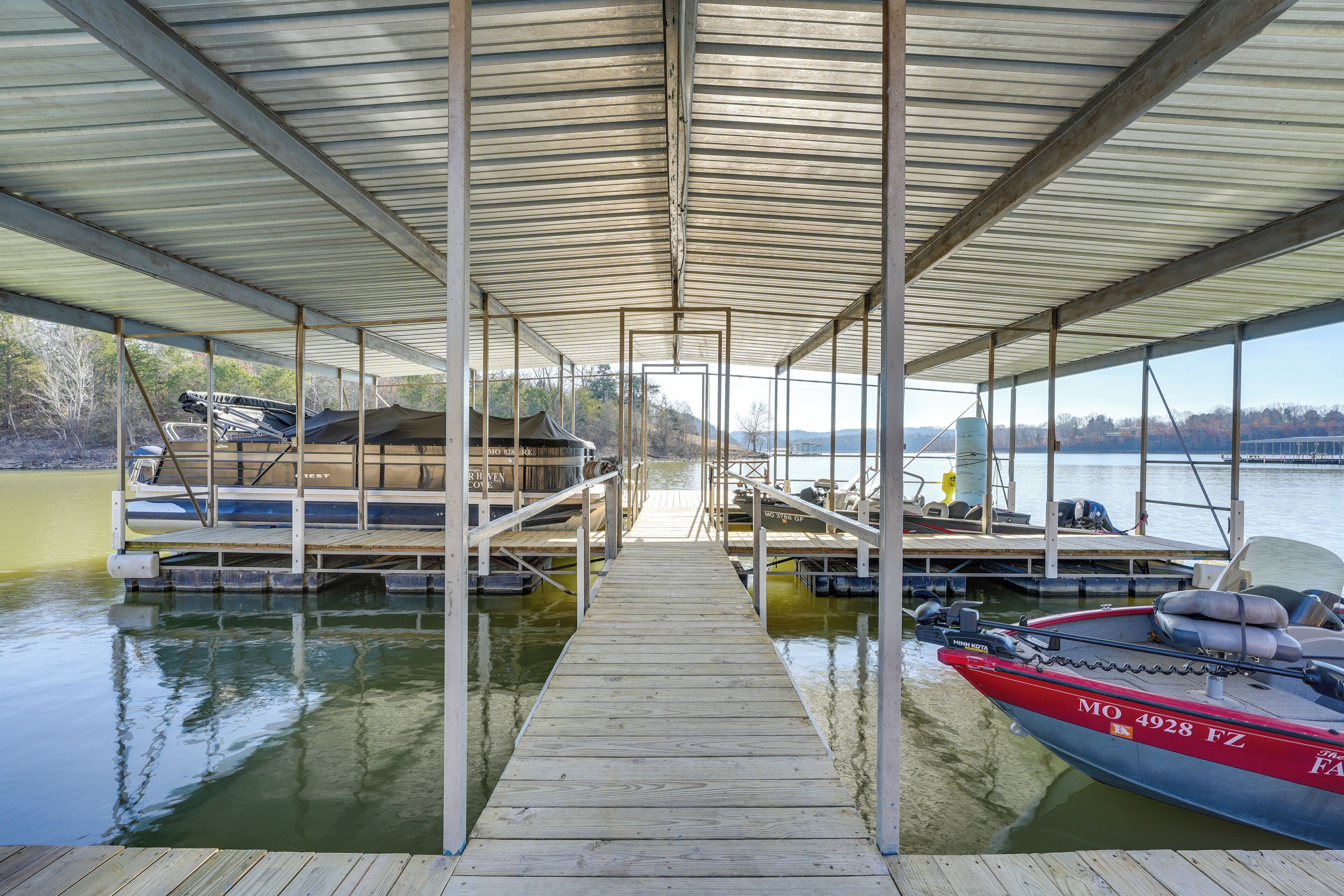 Un quai abrité avec un bateau amarré sur la droite, une passerelle couverte menant au quai, et une eau calme en arrière-plan.