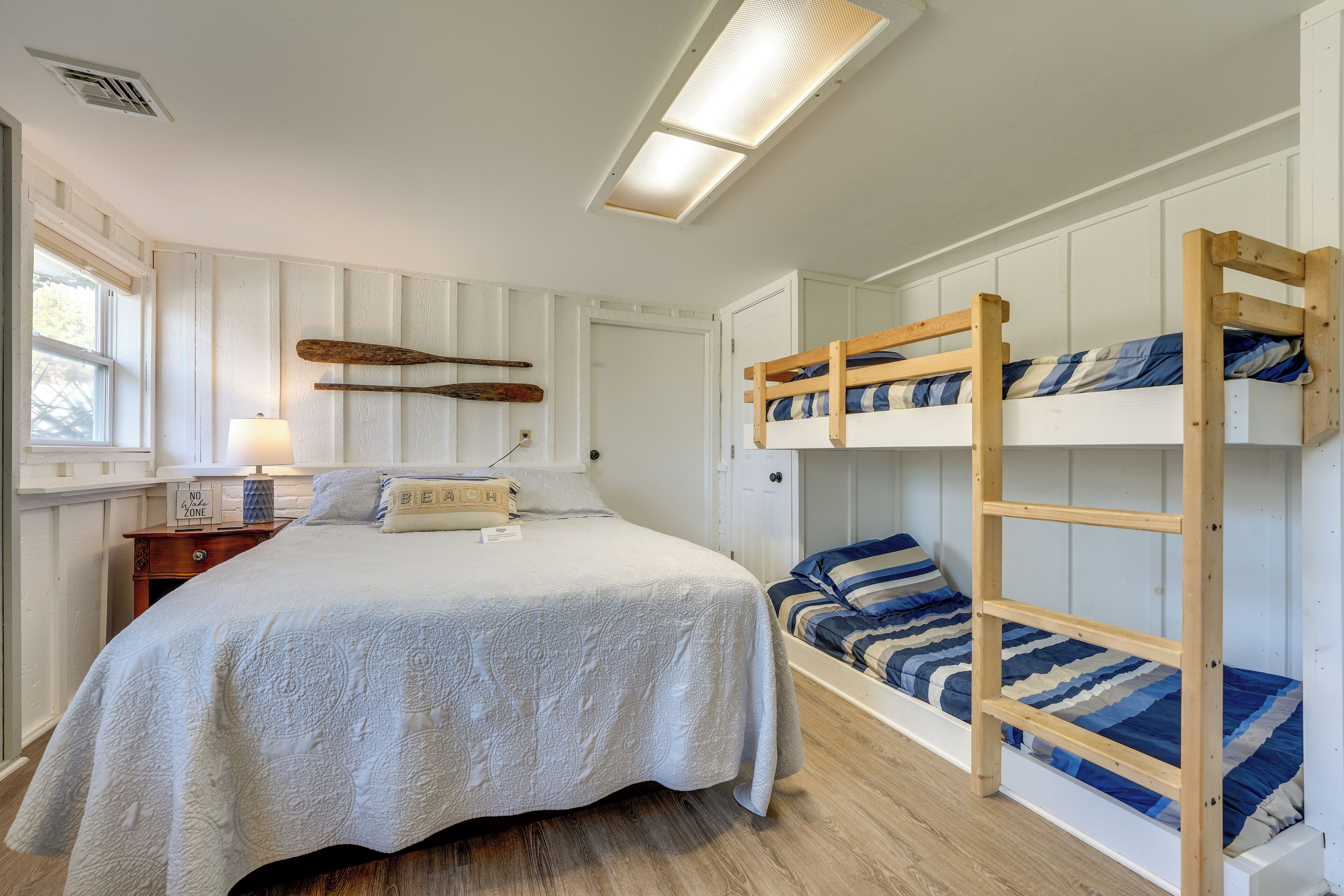 A bedroom with a single bed, a bunk bed, a nightstand, and a lamp.