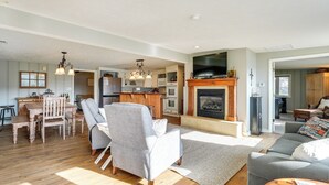 Ein geräumiges Wohnzimmer mit Kamin, einem Essbereich mit Holztisch und Stühlen sowie einer Küche im Hintergrund.