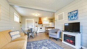 A cozy living room with a sofa, a TV, and a fireplace. A kitchen is visible in the background. - Fish, Boat & Hike On-site: Cape Fair Apartment! (Cape Fair)