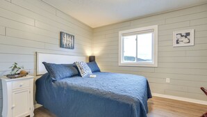 A bedroom with a large bed, a nightstand, a window, and a view of the outdoors. - Fish, Boat & Hike On-site: Cape Fair Apartment! (Cape Fair)