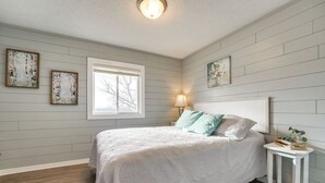 A bedroom with a bed, a nightstand, a window, and wall-mounted artwork. - Lake & Trail Access: Cape Fair Cottage w/ Deck (Cape Fair)
