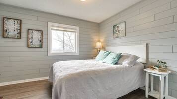 A bedroom with a bed, a nightstand, a window, and wall-mounted artwork.